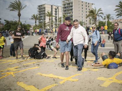 Dos homes intenten trepitjar creus grogues aquest diumenge a la platja de Mataró.