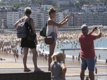 Turistas fotografían la playa de La Concha de San Sebastián.