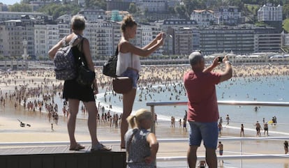 Turistas fotografían la playa de La Concha de San Sebastián.