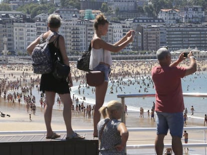 Turistas fotografían la playa de La Concha de San Sebastián.