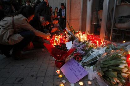 Diverses persones dipositen flors i espelmes a les portes de l'institut Joan Fuster en record del docent assassinat per un alumne.