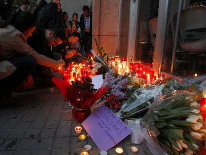 Diverses persones dipositen flors i espelmes a les portes de l'institut Joan Fuster en record del docent assassinat per un alumne.