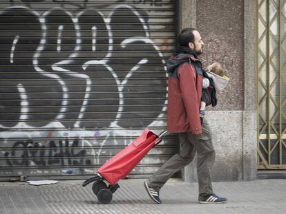 Un pare amb el seu nadó i un carro d'anar a comprar, a Barcelona durant l'estat d'alarma.