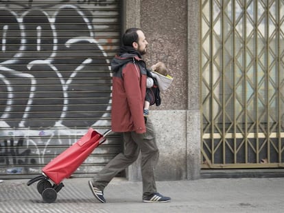 Un pare amb el seu nadó i un carro d'anar a comprar, a Barcelona durant l'estat d'alarma.