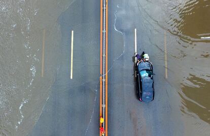 Vista aérea de un oficial de policía ayudando a un conductor a empujar su automóvil en una calle inundada por las fuertes lluvias en la ciudad de Shenyang, en China.