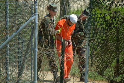 Un detenido es escoltado por dos soldados en la base de Guantánamo en una foto tomada en febrero de 2002.