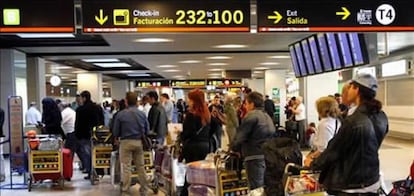 Numerosos pasajeros hacen cola en el aeropuerto de Madrid-Barajas.