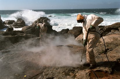 Catástrofe ecológica en Galicia por el hundimiento del petrolero Prestige cargado de fuel oil frente a sus costas. En la imagen, dos personas limpian de chapapote las rocas de la costa de Muxía (Costa de la Muerte), A Coruña, con agua a presión el 3 de abril de 2004.