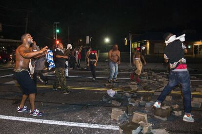 Los manifestantes lanzan piedras e intentan bloquear la calle con ellas durante la protesta por el asesinato de Michael Brown, en Ferguson.