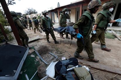 Soldados israelíes retiran cadáveres del kibutz de Kfar Aza atacado por Hamás, el pasado martes.