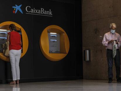 Dos personas en los cajeros dispuestos en el edificio de la sede de Caixabank, en Valencia, Comunidad Valenciana (EspaÃ±a), a 4 de septiembre de 2020. 