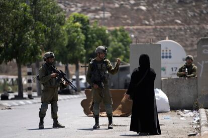 Israeli soldiers speak to a Palestinian woman near the site of an alleged car-ramming attack near Beit Hagai, a Jewish settlement in the hills south of the large Palestinian city of Hebron, Wednesday, Aug. 30, 2023.