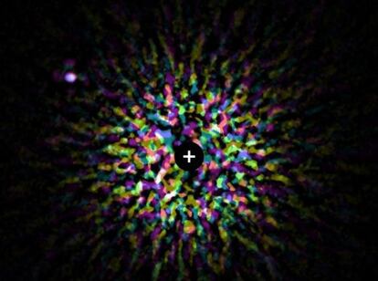 Fotograf&iacute;a del planeta extrasolar Kappa Andromedae b (arriba, a la izquierda) en &oacute;rbita de la estrella que est&aacute; en el centro, pero tapada por una m&aacute;scara oscura generada en ordenador. Los puntos de colores se deben a la luz residual del astro.
