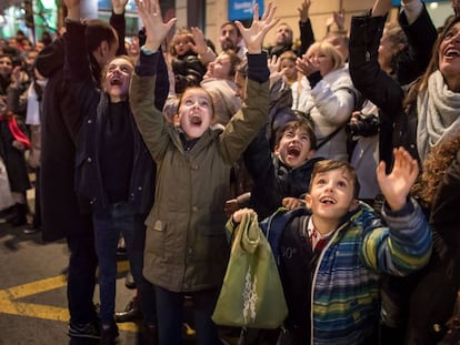 Unos niños esperan ilusionados que los Reyes Magos les tiren caramelos desde sus carrozas en Granada, durante la cabalgata de 2018.