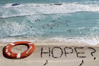 Activistas de Greenpeace demandan "esperanza" para luchar contra el cambio climático en la playa de Cancún.