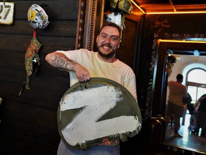 Nikita Hirenko holds the remains of a Russian armored vehicle now used to decorate the Hoppy Hog pub, which he opened in July 2022.