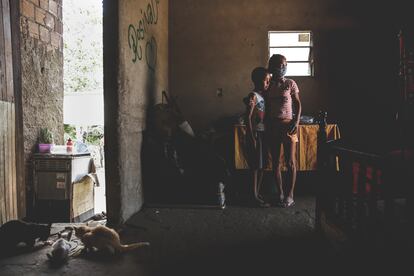 La señora Silva con uno de sus nietos en la sala cocina de su casa de ladrillo y suelo de tierra, en Garanhuns (Pernambuco).