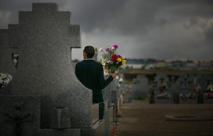 Un hombre sujeta un ramos de flores en el cementerio de Colmenar Viejo, en Madrid. 