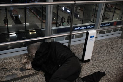 Un hombre duerme en el segundo piso del aeródromo bonaerense mientras un grupo de pasajeros recoge su equipaje recién descargado de un vuelo nacional.