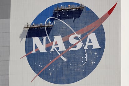 Workers on scaffolding repaint the NASA logo near the top of the Vehicle Assembly Building at the Kennedy Space Center in Cape Canaveral