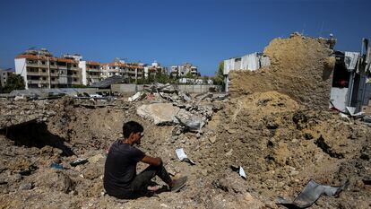 Un libanés, sentado junto al cráter causado por un proyectil israel, en la localidad libanesa de Jiyeh, el 25 de septiembre de 2024.