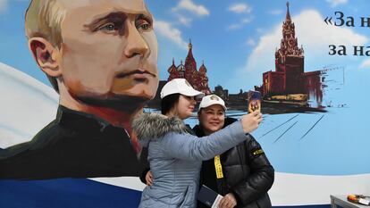 Unas mujeres posan para una foto ante un mural de Vladímir Putin, tras votar este sábado en Donetsk.