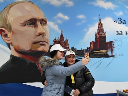 Unas mujeres posan para una foto ante un mural de Vladímir Putin, tras votar este sábado en Donetsk.