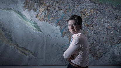 La alcaldesa de Bogotá, Claudia López, posa en su despacho junto a un mapa de la capital de Colombia.