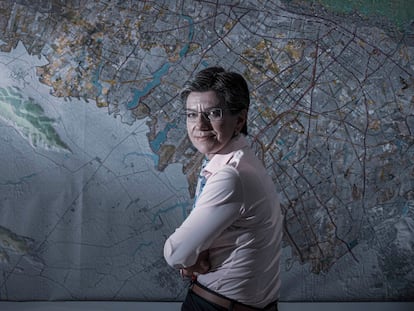 La alcaldesa de Bogotá, Claudia López, posa en su despacho junto a un mapa de la capital de Colombia.