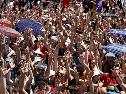 Los acampados de Sol levantan sus manos para votar en la asamblea.