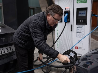 Una persona usa un punto de recarga público para coches eléctricos en Barcelona.