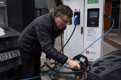 Una persona usa un punto de recarga público para coches eléctricos en Barcelona.