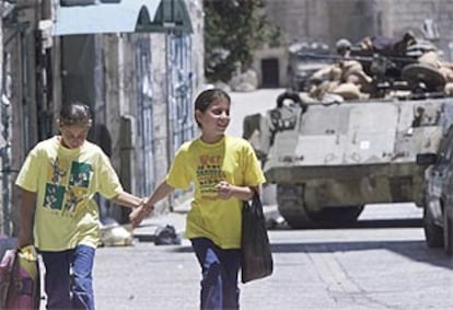 Dos niñas caminan delante de un tanque israelí apostado en las cercanias de la basílica de la Natividad en Belén.