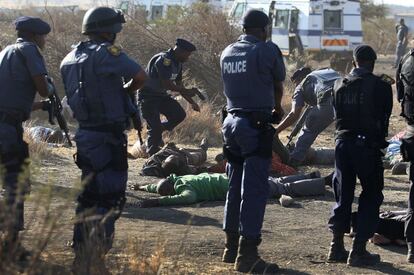 Policías rodean los cuerpos de mineros abatidos durante los enfrentamientos en la mina de platino de Lonmin, cerca de Rustenburg, Sudáfrica. Más de 3.000 mineros llevaban protestando por sus condiciones salariales desde el pasado viernes.