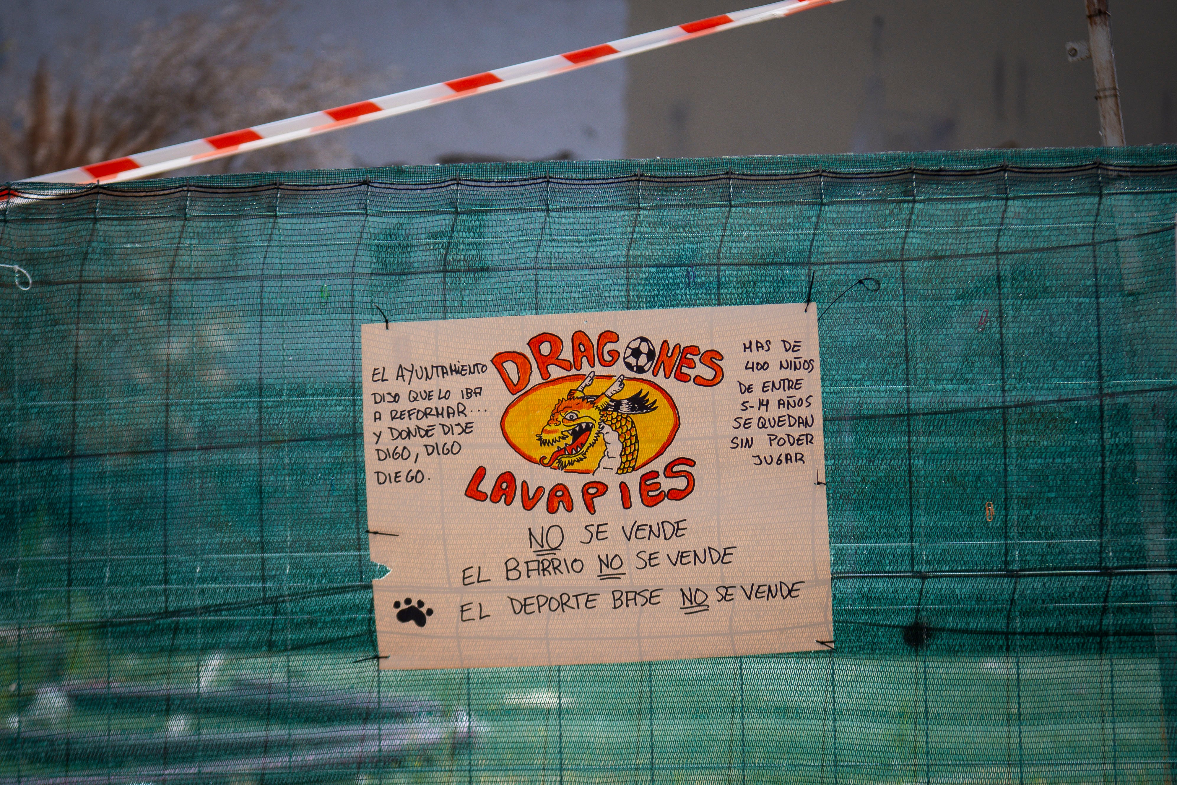 Un cartel de protesta en la valla de obras que rodea al campo de fútbol del club Dragones de Lavapiés. 
