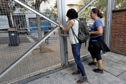 Dos mujeres abren la valla del colegio Torrent D'en Melis de Barcelona, activistas pretenden ocupar los colegios que abrirán el día 1-O para evitar que se impida votar en el referéndum.
