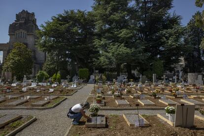 Una mujer coloca flores en la zona del cementerio Monumental de Bérgamo, donde han sido enterradas la mayoría de personas que murieron a causa de la covid-19. La tasa de sepulturas en tierra es normalmente baja, pero el número de fallecimientos fue tan elevado que pueden distinguirse perfectamente todas las tumbas nuevas.