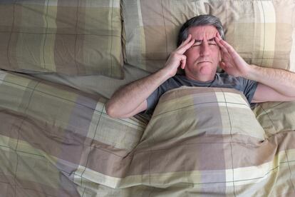 Un hombre trata de dormir en su cama.