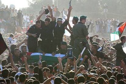 Miles de palestinos rodean el féretro de Yasir Arafat, protegido por hombres armados, en la explanada de la Mukata, su cuartel general, en Ramala.