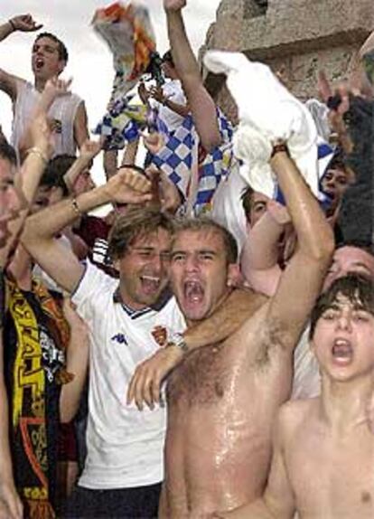 Los jugadores del Zaragoza Slobodan Komljenovic (izqda.) y Jordi Ferrón celebran con los aficionados en la fuente de la Plaza de España de Zaragoza el ascenso.