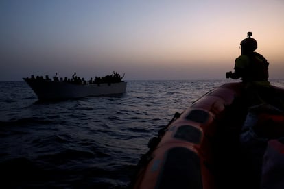 Varios migrantes a bordo de una embarcación hacen señales a los miembros de la ONG Proactiva Open Arms, en el Mediterráneo central, este miércoles.