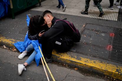 Una pareja se besa sentados sobre la acera, entre manifestantes.