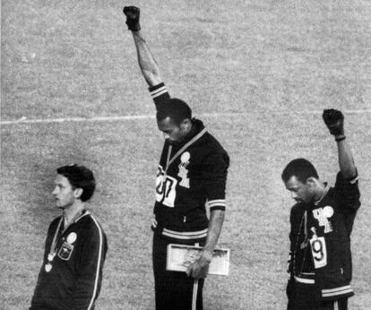 Los atletas estadounidenses Tommie Smith (c) y John Carlos (d), medalla de oro y record mundial, y medalla de bronce, respectivamente, en la prueba de los 200 metros lisos masculinos, saludan con el brazo en alto y el puño cerrado con guante negro, mientras sonaba el himno de Estados Unidos en la ceremonia de entrega de medallas. El gesto corresponde a uno de los signos del Black Power (poder negro) en protesta contra la discriminación racial.