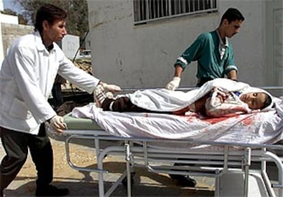 Dos enfermeros trasladan el cuerpo del niño muerto hoy en Gaza a la morgue.