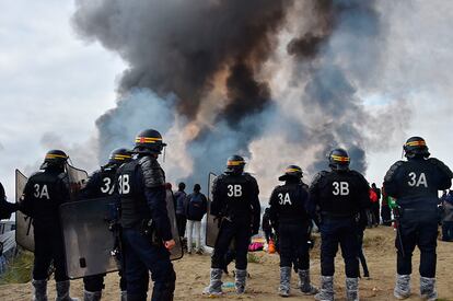 Agentes de la policía francesa vigila el campamento de Calais durante el incendio.