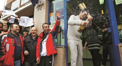 En diciembre de hace dos años, la administración número 12 de Alcalá de Henares repartió dos tercios del premio Gordo de Navidad. En la imagen, su propietario y vecinos del barrio celebrándolo.