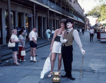 Charlot, um mímico de rua, posa com uma turista em uma rua do bairro francês. A cidade, conhecida como The Big Easy por seu modo descontraído de entender a vida, foi fundada por colonos franceses em 1718 e, em 1763, foi cedida à Espanha, país ao qual pertencia até 1801. New Orleans voltou ser francesa até 1803, quando passou a ser território dos Estados Unidos. A esse multiculturalismo, devemos acrescentar a chegada dos acadianos, os habitantes da América Francesa do Atlântico (Acadia) que falavam sua própria língua, o francês cajun, e o dos africanos escravizados nas ricas plantações de algodão da região.