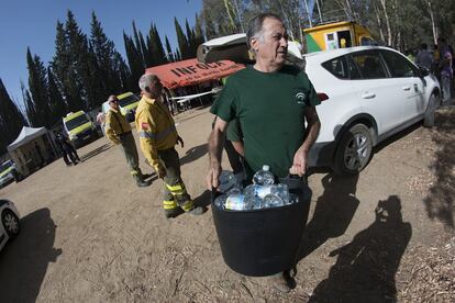 Miembros del Infoca cargan cubos con botellas de agua fría para repartir a los operarios.