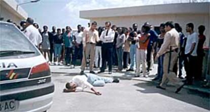 Los inmigrantes del centro de estancia temporal de Ceuta miran a uno de sus compañeros, en el suelo, tras ser golpeado supuestamente por los guardias.