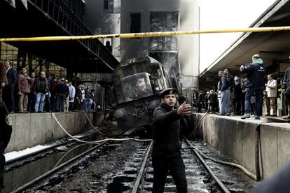Un policía da indicaciones frente a un tren accidentado dentro de la estación de tren Ramsis en El Cairo (Egipto). Un funcionario médico egipcio ha declarado que al menos 20 personas han muerto y decenas han resultado heridas.